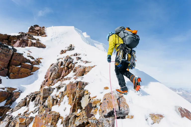 Persona escalando la ladera de una montaña nevada